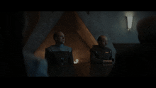 two men sit at a table in a dark room with the words deep substrate foliated kalkite above them