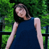 a woman in a blue dress is standing in front of a fence with the word moon on the bottom left