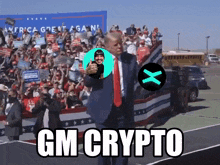 a man in a suit and tie stands in front of a crowd with gm crypto written on the bottom