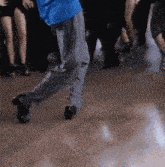 a man in a blue shirt is dancing in front of a group of people