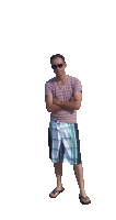 a man standing with his arms crossed wearing plaid shorts and a striped shirt