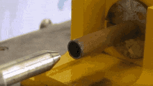 a metal pipe is being drilled into a yellow object