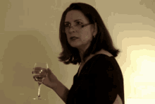 a woman wearing glasses holds a wine glass