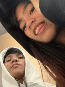 a man and a woman are posing for a picture and the man is wearing a white hoodie
