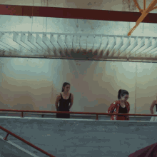 a woman in a black tank top is standing on a balcony