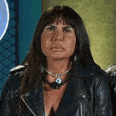 a woman wearing a leather jacket and a necklace is making a face