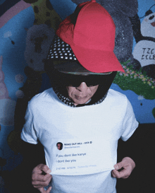 a man wearing a red hat and sunglasses is holding a t-shirt with a tweet from xxxtentacion