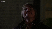 a woman with wet hair is screaming in the rain with her fists in the air .