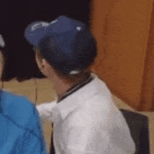 a man wearing a blue hat and a white shirt is sitting in a chair
