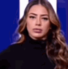 a woman in a black turtleneck is making a funny face .