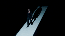 a man in a black suit is walking on a white carpet