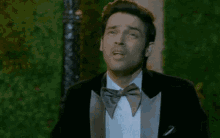 a man in a tuxedo is holding his hands up in the air
