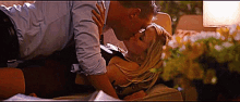 a man and a woman kissing on a bed with flowers in the background