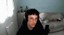 a young man wearing headphones and glasses is sitting in front of a microphone