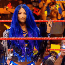 a woman with blue hair is standing in a wrestling ring