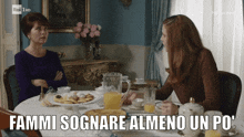 two women sitting at a table with the words fammi sognare almeno un po