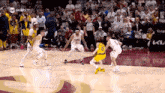 a basketball game is being played on a court in front of a crowd .