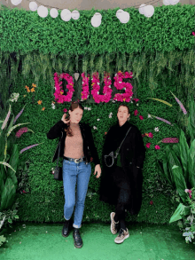two women standing in front of a wall with the word duos in pink flowers