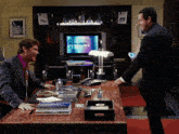two men are standing in front of a tv that says ammer
