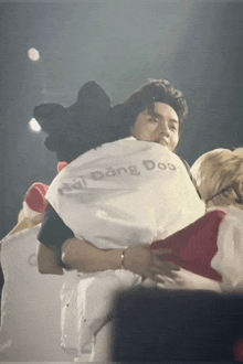 a man wearing a shirt that says dong doo is hugging another person