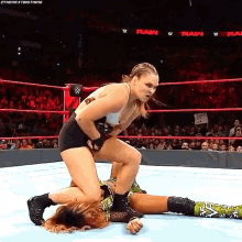 two women are wrestling in a wrestling ring with a crowd watching .