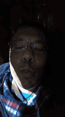 a man wearing glasses and a plaid shirt is laying down with his eyes closed