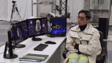 a man sits at a desk in front of a computer monitor which says ' ii ' on it