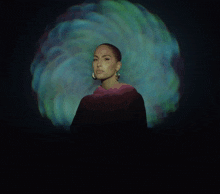 a woman is standing in front of a blue and green light