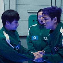 a man with purple hair is shaking hands with two other men