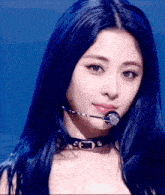 a woman with long blue hair is wearing a microphone around her neck .