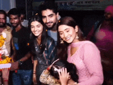 a group of people are posing for a picture with a little girl in a crowd of people .