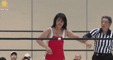 a woman in a red swimsuit is standing in a wrestling ring