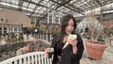 a woman eating an ice cream cone in a greenhouse