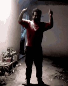 a man in a red shirt flexes his muscles in a dark room