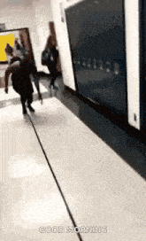 a group of people are walking down a hallway in a school with lockers .