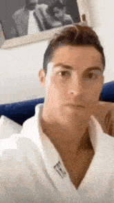 a man in a white robe is taking a selfie in front of a picture of himself .