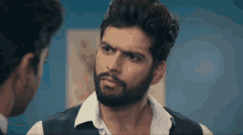 a man with a beard looks at another man in a suit