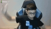 a young boy is sitting in a chair with his arms outstretched and wearing glasses .