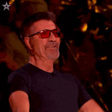 a man wearing red glasses and a black shirt is raising his arms in the air