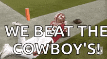 a football player is laying on the ground on a field with the words `` we beat the cowboy 's '' .