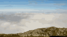 a view of a mountain covered in clouds with a blue sky in the background