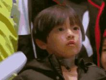 a young boy in a jacket is making a funny face while sitting in a chair .