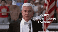 a man in a tuxedo and bow tie stands in front of a microphone and says " it 's my 3rd language