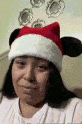 a woman wearing a santa hat with mickey mouse ears on it