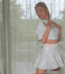 a woman in a white dress stands in front of a window with her arms outstretched