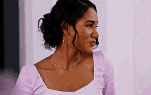 a woman wearing a purple shirt and hoop earrings is smiling .