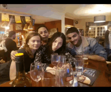 a group of people sitting at a table with a bottle of stella artois on it