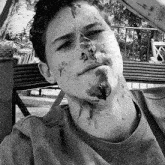 a black and white photo of a young man with blood on his face and neck