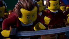 a group of lego figures are standing in a line and one of them is holding a sword