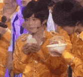 a boy in a yellow shirt is holding a bowl of food in his hand .